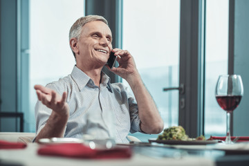 Enjoying vacation. Joyful man keeping smile on his face and actively gesticulating while talking