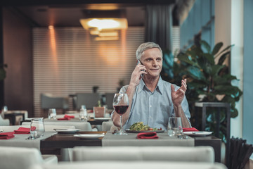Having dinner. Delighted male person expressing positivity while going to eat salad