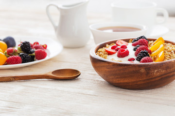 granola with berries on white wooden background