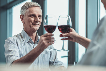 Our date. Cheerful mature man keeping smile on his face while looking at his wife