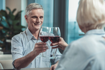 Love you. Handsome male person raising hand while touching glasses with his partner