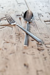 Gabel und Löffel auf gravierter Tischplatte 