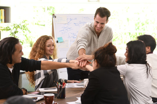 Group of businesspersons stacking hands together in agreement in a meeting at office