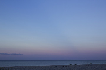 A stone beach in Jylland, Denmark, with the ocean in the distance and a sky colored violet and blue at dusk.