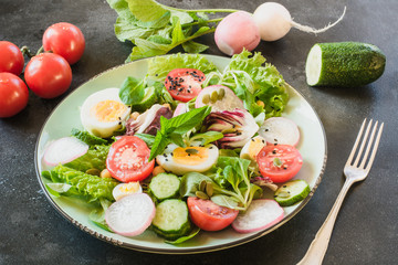 Healthy salad with vegetables and eggs on black table. Close up, copy space. Balanced diet for weight loss.