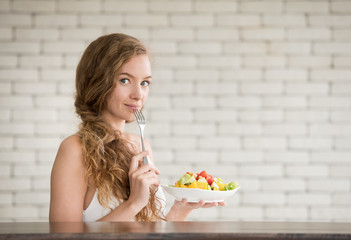 Beautiful young woman in joyful postures with hand holding salad bowl