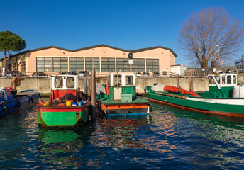 Fototapeta na wymiar colorful boats loaded with tools moored in front of an industrial warehouse, Venice. Italy