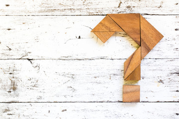 Tangram puzzle in question mark shape on old white wood background
