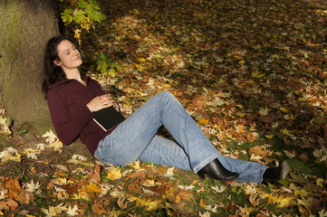 woman relaxing in autumn scene, sleeping under a tree