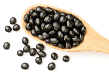 uncooked black bean in the wooen spoon, isolated on white, top view