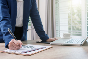 Business woman hands with pen writing notebook on office desk table close up. Business concept.