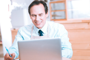 Fototapeta premium Have idea. Pleased businessman keeping smile on his face while and counting incomes