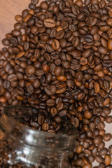 Coffee beans, poured from a glass transparent jar.