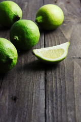 Green lemons on dark wooden surface