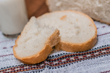 A glass of milk and bread on a wooden table.
