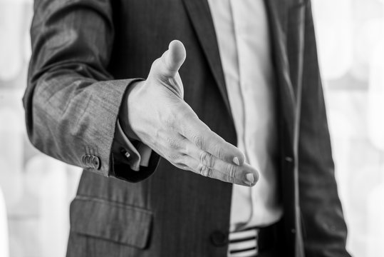 Black and white image of a businessman offering hand in handshake