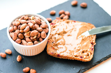 Peanut butter sandwich on chalk board and raw peanuts