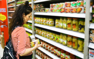 Sale, shopping, consumerism, people concept. Woman shopping and comparing food products in...
