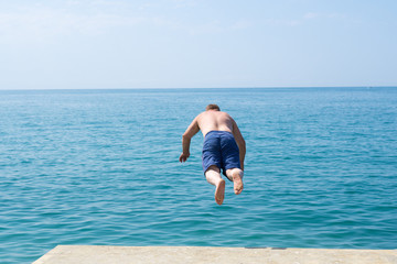 A man jumps into the sea from the pier
