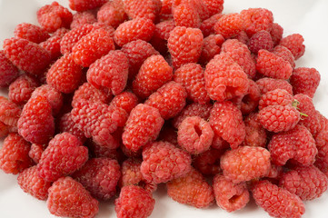 Background of raspberries. Fresh raspberries closeup on white background. Top view. Background of red berries. Various fresh summer fruits. Red raspberries. Red food.