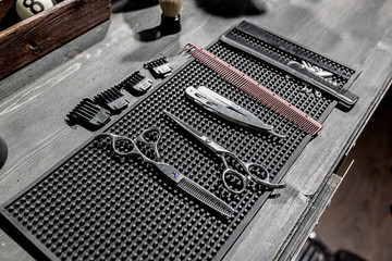 Fototapeta premium The tools of the hairdresser lie on a black mat on the desktop