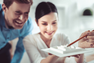 High spirits. Amazing female person keeping smile on her face while examining model of settlement