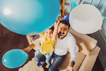 Father and son activity. Cheerful jolly boy and man having fun with balloons while laughing
