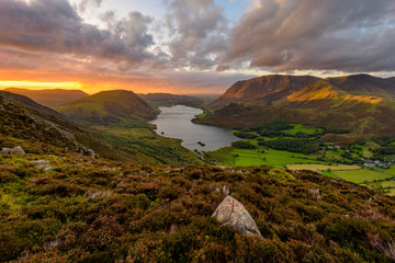 Moody dramatic clouds over high up view of Crummock Water at sunset. Lake District, UK.