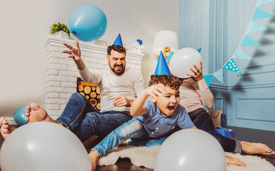 Party in progress. Optimistic enthusiastic family laughing while playing on floor