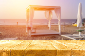 old wooden table on the beach at sunset in golden tone  
