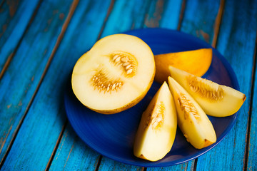 Yellow cut melon on a blue plate and blue wooden boards - 222008086