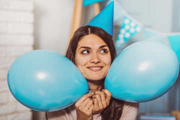 In anticipation. Nice energetic woman holding balloons while looking aside