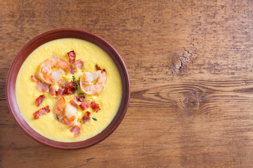 Creamy corn vegetable soup with shrimps and bacon. View from above, top studio shot