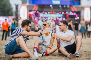 Friends drinking beer and having fun at music festival  