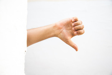 male adult hand showing thumbs down gesture from behind a wall