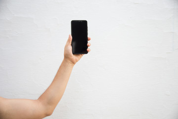 a hand rising a mobile phone against white background