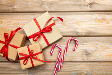 Gift boxes with red ribbon and candy canes on wooden background, copy space, top view