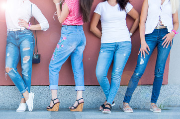 Women near the wall in jeans and t-shirts. Women's party before the wedding. Girls with flowers and...