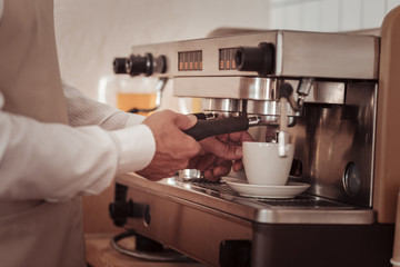 Coffee preparation. Cup of coffee standing in the coffee machine while being prepared there