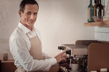 Professional equipment. Skilled male barista using professional equipment while preparing coffee