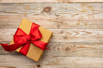 Gift box with red ribbon on wooden background, copy space, top view