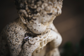 Two wedding rings on a stone statue of a boy
