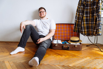 young man sit on floor . valise packing for trip.travel concept. copy space.