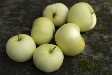 Pale yellow apples on a dark wooden surface.Pale yellow apples on a dark old  wooden table.
