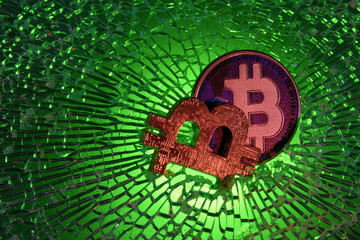 Bitcoin crypto currency bear market or depression concept, metal clamp squeezing  Bitcoin physical coin , crisis on cryptocurrency investment trading metaphor.On broken glass background