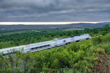 Railway and blurred fast train in the country, cloudy sky