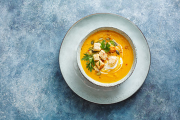 Pumpkin soup with cream and pumpkin seeds served with crackers and fresh herbs. Concept for healthy...