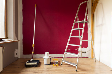 Tools for coloring, paint roller, brush, aluminium leader. Wall partly collored.