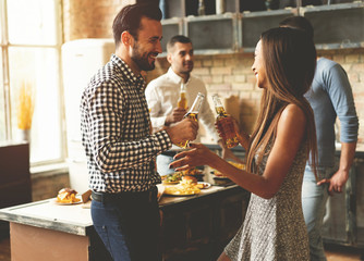 Party with best friends. Group of cheerful young people enjoying home party with snacks and drinks while communicating on the kitchen.