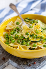 Plate with pasta, zucchini and green peas.